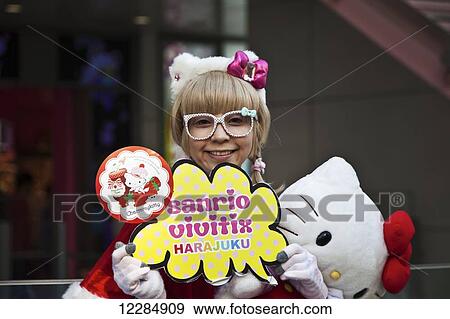 Stock Photo - A girl posing with eyeglasses and hello kitty stuffed toy; Tokyo, Japan. Fotosearch