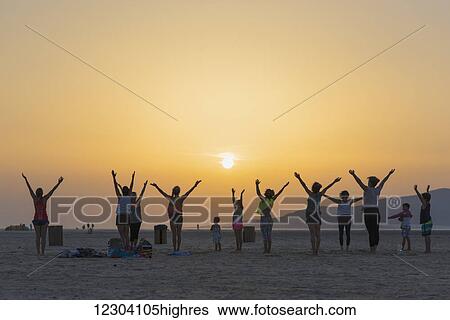 A group of women with some children doing yoga on a beach at sunset; Tarifa, Andalusia, Spain View Large Photo Image Stock Photograph - A group of women with some children doing yoga on a beach at sunset; Tarifa, Andalusia, Spain. Fotosearch