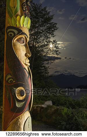 A large totem pole lit up at night in Sitka National Historic Park with the moon and clouds in the background; Sitka, Alaska, United States of America View Large Photo Image Stock Photograph - A large totem pole lit up at night in Sitka National Historic Park with the moon and clouds in the background; Sitka, Alaska, United States of America. Fotosearch