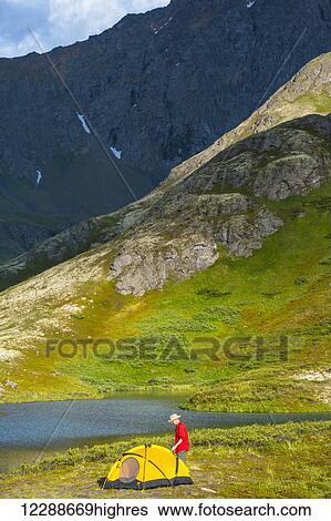 Stock Photograph - A man at his campsite at Hanging Valley in South Fork near Eagle River on a summer day in South Central Alaska.. Fotosearch