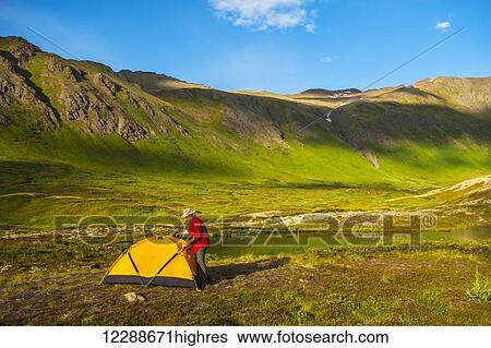 Stock Photograph - A man at his campsite at Hanging Valley in South Fork near Eagle River on a summer day in South Central Alaska.. Fotosearch