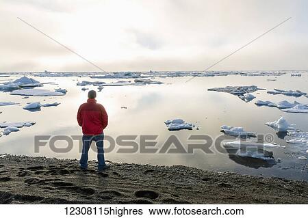 A man at the shore of the Arctic Ocean looking out towards the sun setting through dense fog, Barrow, North Slope, Arctic Alaska, USA, Summer View Large Photo Image Stock Photograph - A man at the shore of the Arctic Ocean looking out towards the sun setting through dense fog, Barrow, North Slope, Arctic Alaska, USA, Summer. Fotosearch