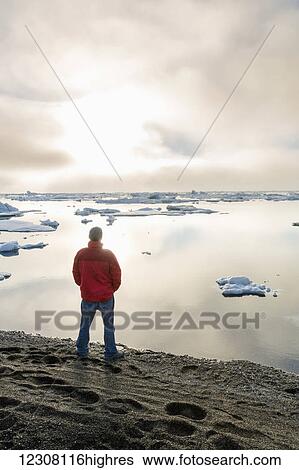 A man at the shore of the Arctic Ocean looking out towards the sun setting through dense fog, Barrow, North Slope, Arctic Alaska, USA, Summer View Large Photo Image Stock Photograph - A man at the shore of the Arctic Ocean looking out towards the sun setting through dense fog, Barrow, North Slope, Arctic Alaska, USA, Summer. Fotosearch