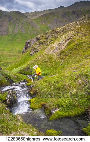 A man filling his water bottle in Hanging Valley in South Fork near Eagle River on a summer day in South Central Alaska. View Large Photo Image Stock Photograph - A man filling his water bottle in Hanging Valley in South Fork near Eagle River on a summer day in South Central Alaska.. Fotosearch