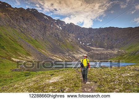 Stock Photograph - A man hiking in Hanging Valley in South Fork near Eagle River on a summer day in South Central Alaska.. Fotosearch