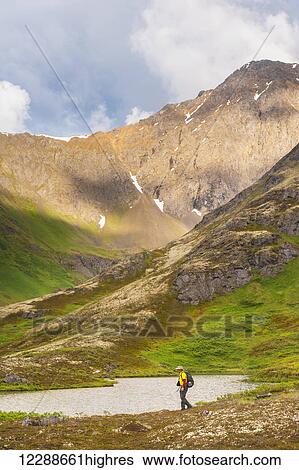 A man hiking in Hanging Valley in South Fork near Eagle River on a summer day in South Central Alaska. View Large Photo Image Stock Photograph - A man hiking in Hanging Valley in South Fork near Eagle River on a summer day in South Central Alaska.. Fotosearch