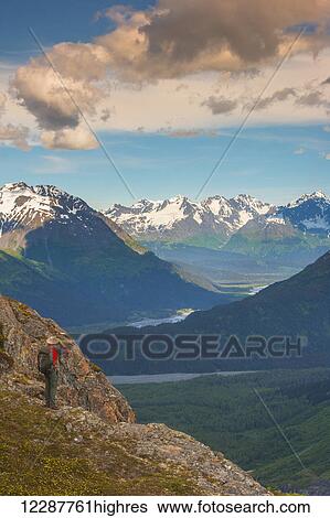 Stock Photograph - A man hiking near the Harding Icefield Trail with the Chugach mountains and the Resurrection Valley in the background, Kenai Fjords National Park, Southcentral Alaska. Fotosearch