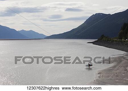 Stock Photograph - A man paddle-boards out in Turnagain Arm in Southcentral Alaska.. Fotosearch