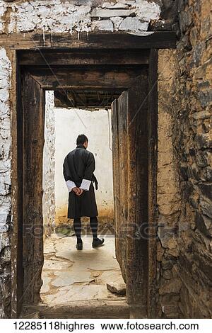 Stock Photograph - A man walking on a path, Tachog Lhakhang Dzong; Paro, Bhutan. Fotosearch