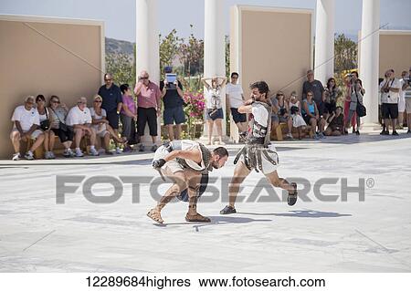 A pair of actors dressed as gladiators fight in a duel in front of a crowd of tourists at a Greek history attraction in Turkey; Kusadasi, Izmir, Turkey View Large Photo Image Stock Photograph - A pair of actors dressed as gladiators fight in a duel in front of a crowd of tourists at a Greek history attraction in Turkey; Kusadasi, Izmir, Turkey. Fotosearch