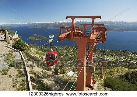 A red gondola arrives at the summit of a mountain overlooking a large lake with snow-capped mountains in the distance; Bariloche, Argentina View Large Photo Image Stock Photograph - A red gondola arrives at the summit of a mountain overlooking a large lake with snow-capped mountains in the distance; Bariloche, Argentina. Fotosearch