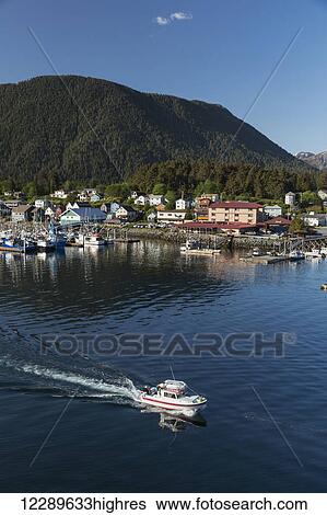 Stock Photograph - A small boat departs from Sitka Harbor on a clear day, Southeast Alaska, USA, Summer. Fotosearch