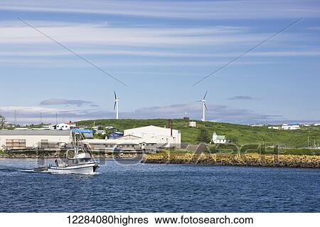 Stock Photograph - A small fishing boat motors past a breakwater in Sand Point Harbor, Southwestern Alaska, USA, Summer. Fotosearch