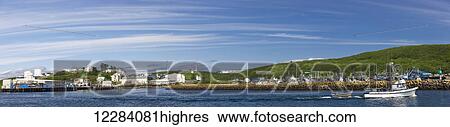 Stock Photograph - A small fishing boat motors past a breakwater in Sand Point Harbor, Southwestern Alaska, USA, Summer. Fotosearch