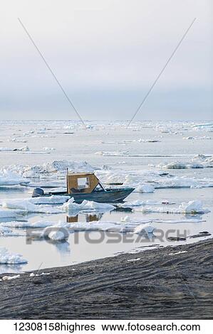 Stock Photograph - A small outboard boat motors through icebergs in the Arctic Ocean on a calm evening, 0rth Slope, Barrow, Arctic Alaska, USA, Summer. Fotosearch
