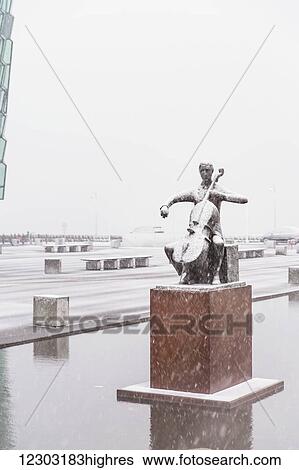 A statue of cellist Erling Blondal Bengtsson by sculptor Olof Palsdottir sits outside the Harpa Public Concert Hall, snow falling and covering the statue; Reykjavik, Iceland View Large Photo Image Stock Photograph - A statue of cellist Erling Blondal Bengtsson by sculptor Olof Palsdottir sits outside the Harpa Public Concert Hall, snow falling and covering the statue; Reykjavik, Iceland. Fotosearch