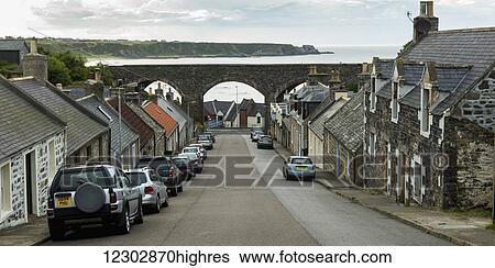 Stock Photograph - A street lined with houses leading down to the ocean; Cullen, Scotland. Fotosearch