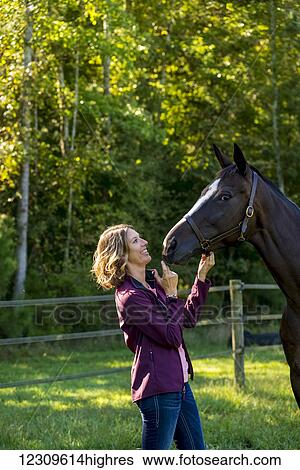 Stock Photograph - A teenage girl stands with her female thoroughbred horse at Folly Farm; Chapel Hill, North Carolina, United States of America. Fotosearch