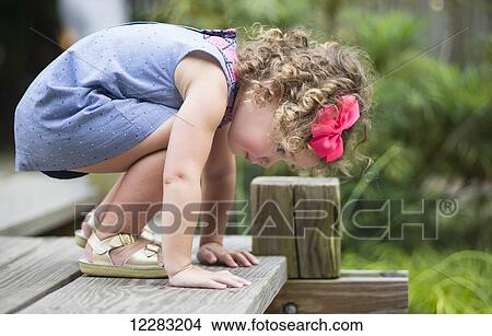 A three-year-old girl looks over the edge of a wooden deck at JC Raulston Arboretum; Raleigh, North Carolina, USA View Large Photo Image Picture - A three-year-old girl looks over the edge of a wooden deck at JC Raulston Arboretum; Raleigh, North Carolina, USA. Fotosearch