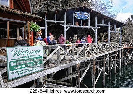 Stock Photograph - A tour group enjoys outdoor eating at The Saltry restaurant in Halibut Cove, Southcentral Alaska. Fotosearch
