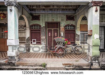 Stock Photograph - A trishaw or tricycle rickshaw sit overnight at it's owners door waiting to go into service; Georgetown, Malaysia. Fotosearch