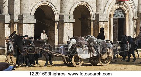 Stock Photograph - A wagon pulled by horses in a street with pedestrians; Montepulciano, Toscana, Italy. Fotosearch