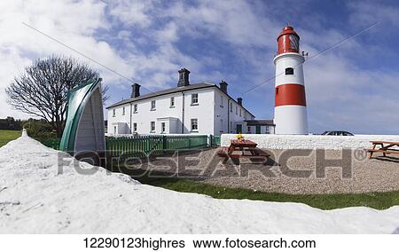 Stock Photograph - A white path beside a red and white lighthouse and building, picnic tables in a seating area; South Shields, Tyne and Wear, England. Fotosearch