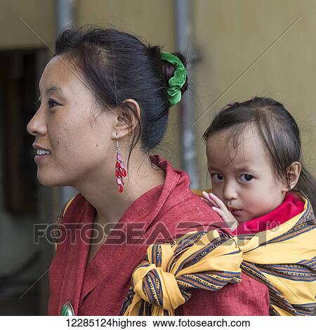 A woman carrying a baby girl on her back; Paro, Bhutan View Large Photo Image Stock Photograph - A woman carrying a baby girl on her back; Paro, Bhutan. Fotosearch