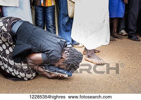 A woman kneels on the street beside an actor reenacting Jesus Christ on Good Friday; Gulu, Uganda View Large Photo Image Stock Photograph - A woman kneels on the street beside an actor reenacting Jesus Christ on Good Friday; Gulu, Uganda. Fotosearch