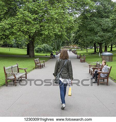 A woman walking down a path in Princes Street Gardens lined with benches and trees; Edinburgh, Scotland View Large Photo Image Stock Photograph - A woman walking down a path in Princes Street Gardens lined with benches and trees; Edinburgh, Scotland. Fotosearch