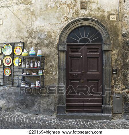Stock Photograph - A wooden door and a display unit with colourful ceramics on display; Orvieto, Umbria, Italy. Fotosearch