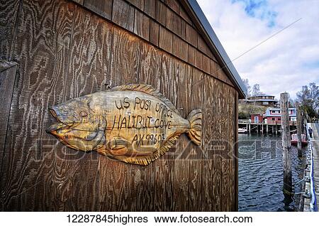 Stock Photograph - A wooden sign in the shape of a halibut announces the U. S. Post Office in Halibut Cove, Southcentral Alaska. Fotosearch