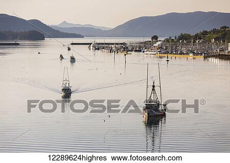 Stock Photograph - Aerial of fishing boats heading towards harbor during sunset, Sitka, Southeast Alaska, USA, summer. Fotosearch