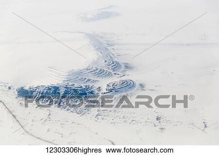 Stock Photograph - Aerial view of an oil field road cutting past small hills covered in snow on the tundra, North Slope, Arctic Alaska, USA, Winter. Fotosearch
