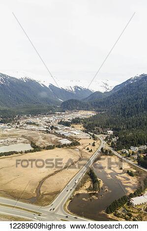 Stock Photograph - Aerial view of Glacier Highway towards the Juneau airport with snow capped peaks in the background, Juneau, Southeast Alaska, USA, Spring. Fotosearch