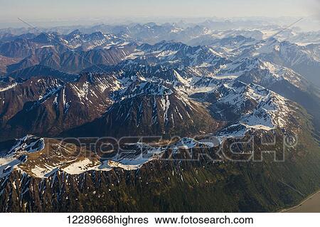 Stock Photograph - Aerial view of snow covered peaks along the Turnagain Arm in the Chugach Mountains, Southcentral Alaska, USA, Summer. Fotosearch