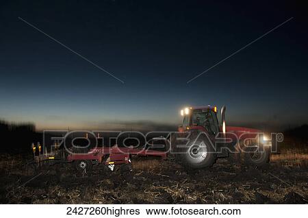 Agriculture - A tractor pulling a disk ripper at dusk tills a field of corn stalks and residue after the harvest, preparing the field for the winter fallow period / near Northrop Minnesota, USA. View Large Photo Image Stock Photograph - Agriculture - A tractor pulling a disk ripper at dusk tills a field of corn stalks and residue after the harvest, preparing the field for the winter fallow period / near Northrop Minnesota, USA.. Fotosearch
