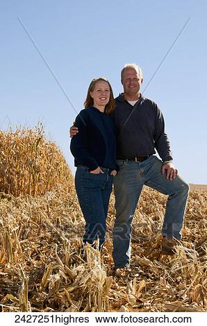 Agriculture - Farmer husband and wife pose together in a partially harvested grain corn field in Autumn / near Sioux City, Iowa, USA. View Large Photo Image Stock Photograph - Agriculture - Farmer husband and wife pose together in a partially harvested grain corn field in Autumn / near Sioux City, Iowa, USA.. Fotosearch