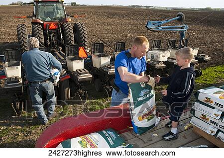 Stock Photograph - Agriculture - Three generations of family farmers loading their planter with corn seed in preparation for spring planting / near Northrop, Minnesota, USA.. Fotosearch