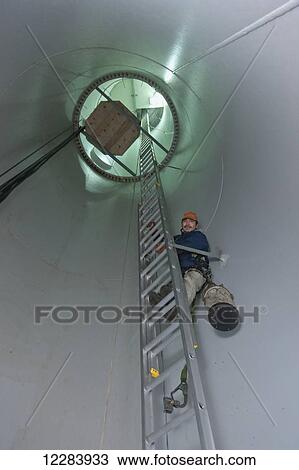 Alaska native wind turbine technican climbing a ladder inside the turbine, wearing a tool bag and harness, St. Paul Island, Southwestern Alaska, USA, Summer View Large Photo Image Stock Image - Alaska native wind turbine technican climbing a ladder inside the turbine, wearing a tool bag and harness, St. Paul Island, Southwestern Alaska, USA, Summer. Fotosearch