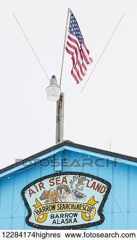 Stock Photograph - An American Flag flies above the Barrow Search and Rescue Office, Barrow, North Slope, Arctic Alaska, USA, Winter. Fotosearch