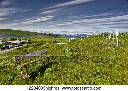 Stock Photograph - An old weathered bench sits among grave markers in the Sand Point graveyard, Southwestern Alaska, USA, Summer. Fotosearch