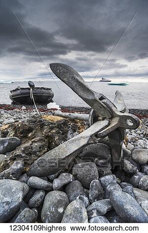 Stock Photograph - Anchor on shingle beach with inflatable behind; Antarctica. Fotosearch