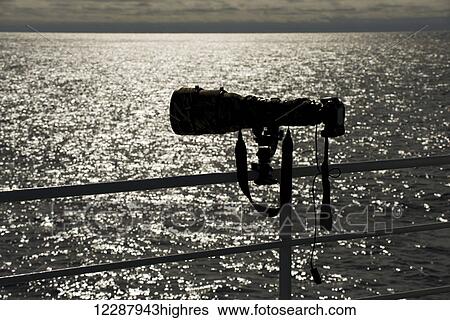 Stock Photograph - Backlit camera with release cable on railing; Spitsbergen, Svalbard, Norway. Fotosearch
