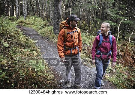 Stock Photograph - Backpacking couple walks a forested trail in the Chugach National Forest of Southcentral Alaska. Fotosearch