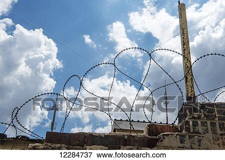 Stock Photo - Barbed wire along unkept brick wall; Soweto, Gauteng, South Africa. Fotosearch