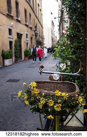Stock Photograph - Bike with basket decorated with flowers in a narrow street; Rome, Italy. Fotosearch