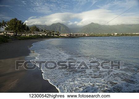 Stock Photograph - Black Sand beach, condos and hotels, Amala Beach, with Iao Valley in the background; Kahalui, Maui, Hawaii, United States of America. Fotosearch