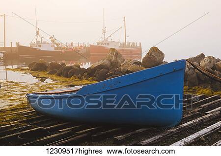 Stock Photograph - Blue rowboat at Bear Point Wharf on a foggy morning; Bear Point, Nova Scotia, Canada. Fotosearch