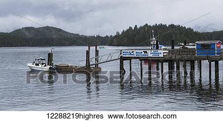 Stock Photograph - Boat at the end of the dock and signs advertising whale watching and bear watching, Hot Springs Cove; Tofino, British Columbia, Canada. Fotosearch